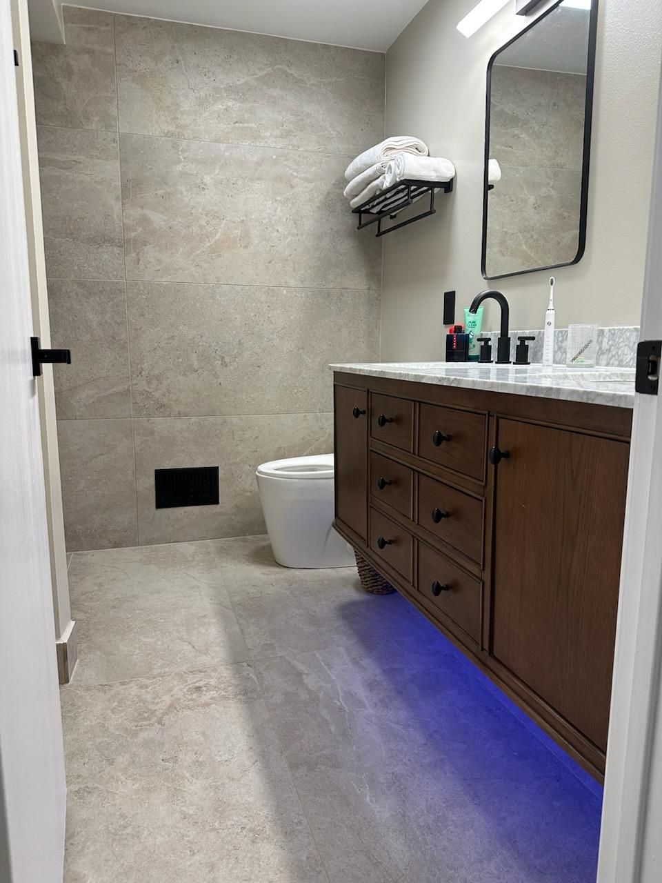 Fully tiled bathroom with floating vanity, mirror, and toilet