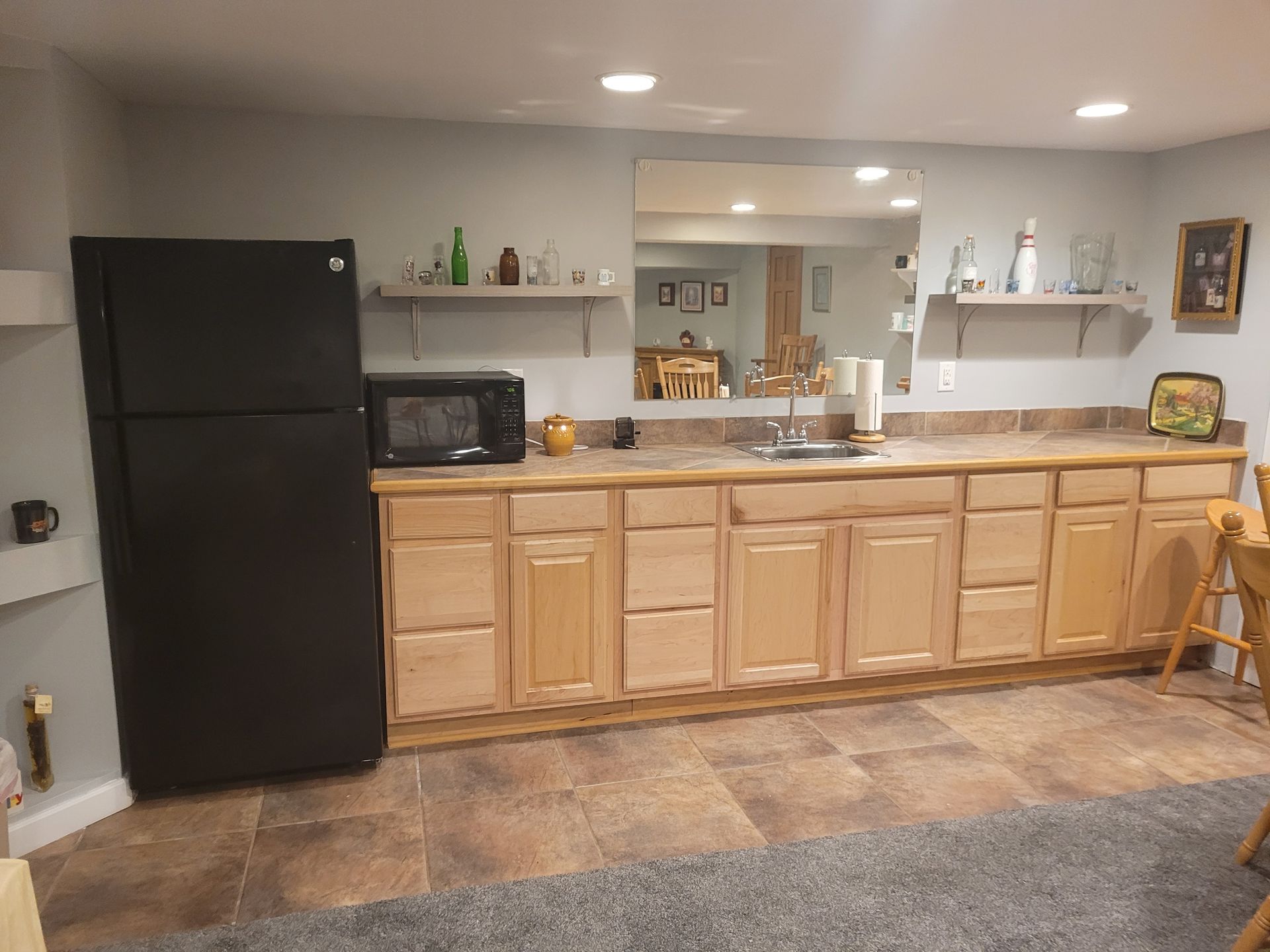 Basement kitchenette with cabinets and fridge