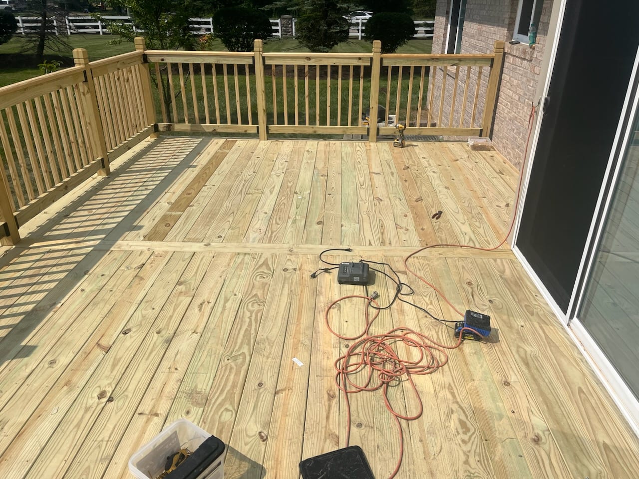 Newly built wood deck with railings on a tan-brick home