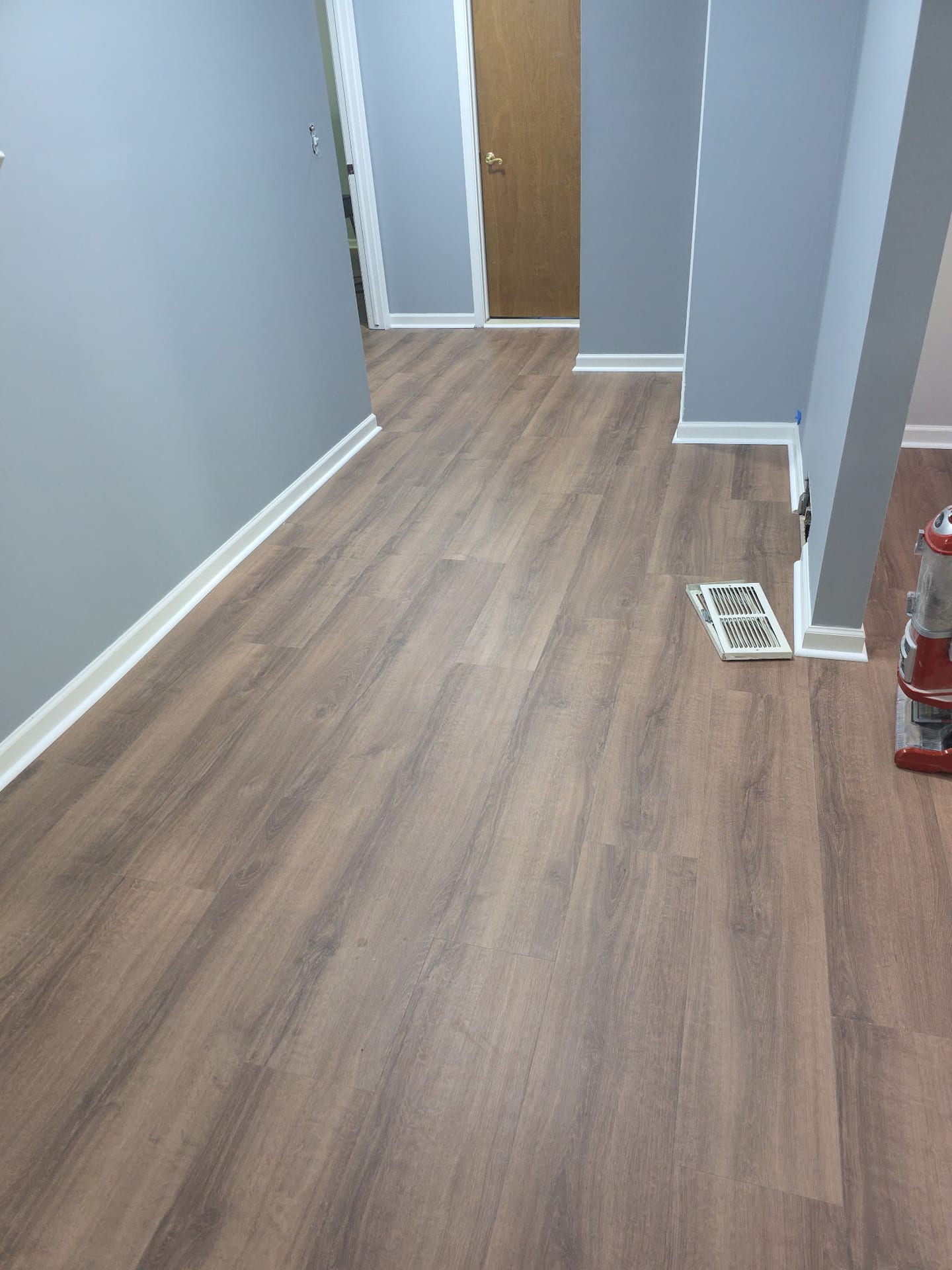Wood-look luxury vinyl plank installed down a hallway with gray walls