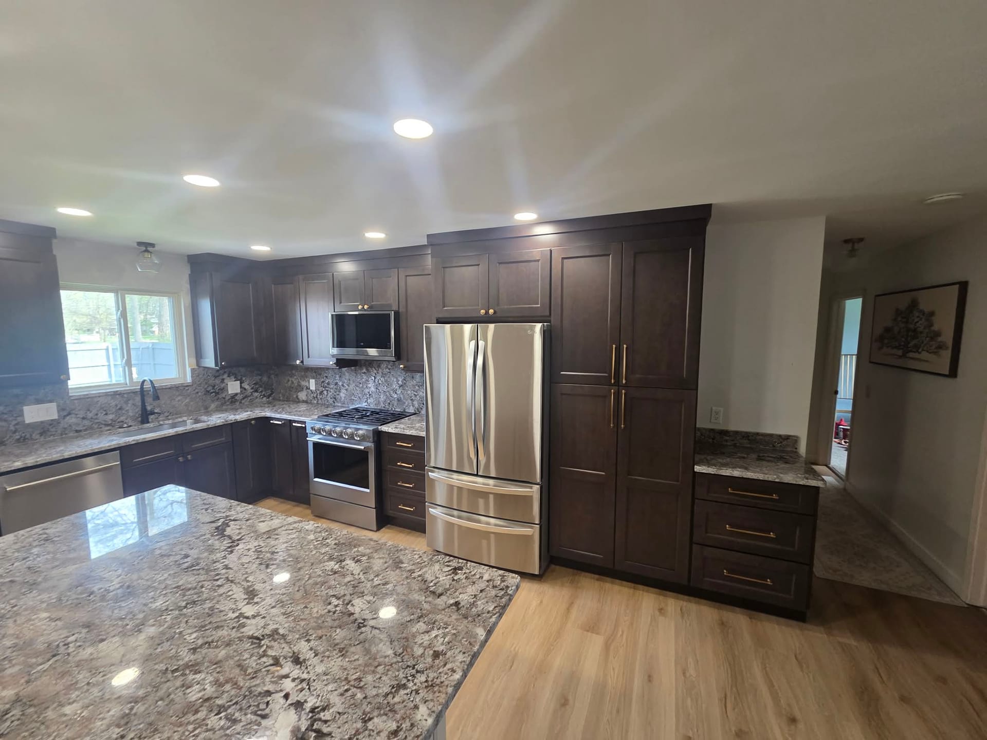 Modern kitchen with overhead recessed lighting, gray island, and dark cabinets
