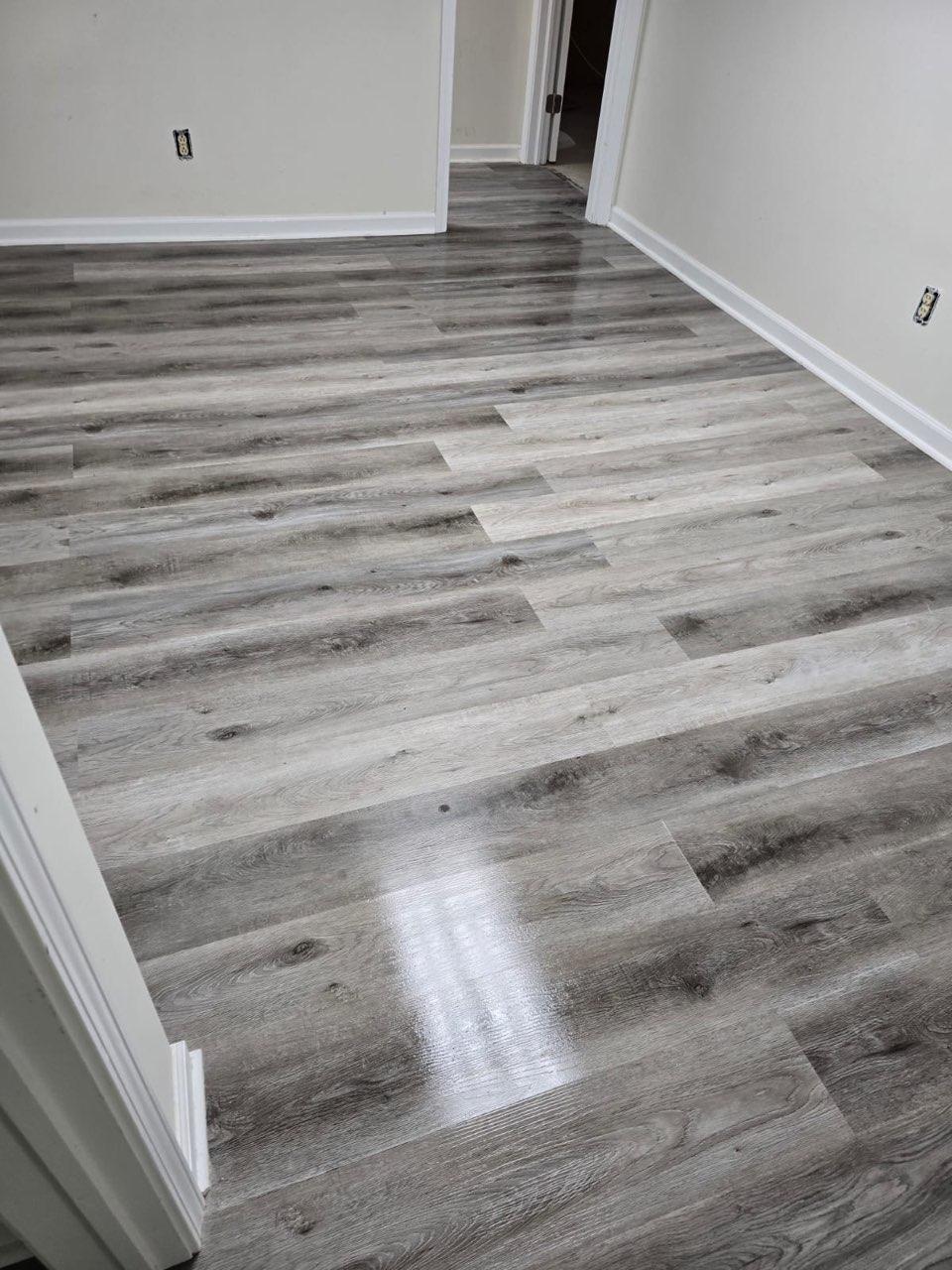 Wide-plank vinyl flooring in an open kitchen with white shaker cabinets